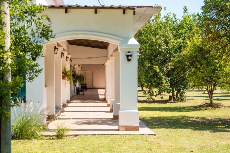 A covered passage between the house and green spaces.