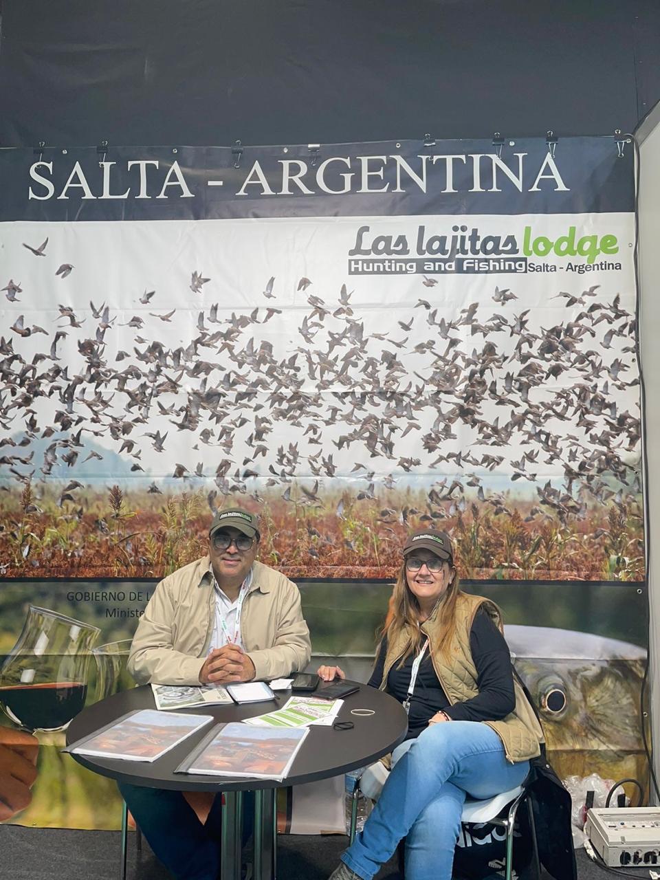 Carlos and Patricia seated at a hunting and fishing booth.